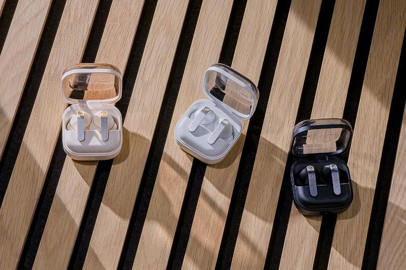 Galaxy Buds4 earbuds and charging cases on a wooden bench.